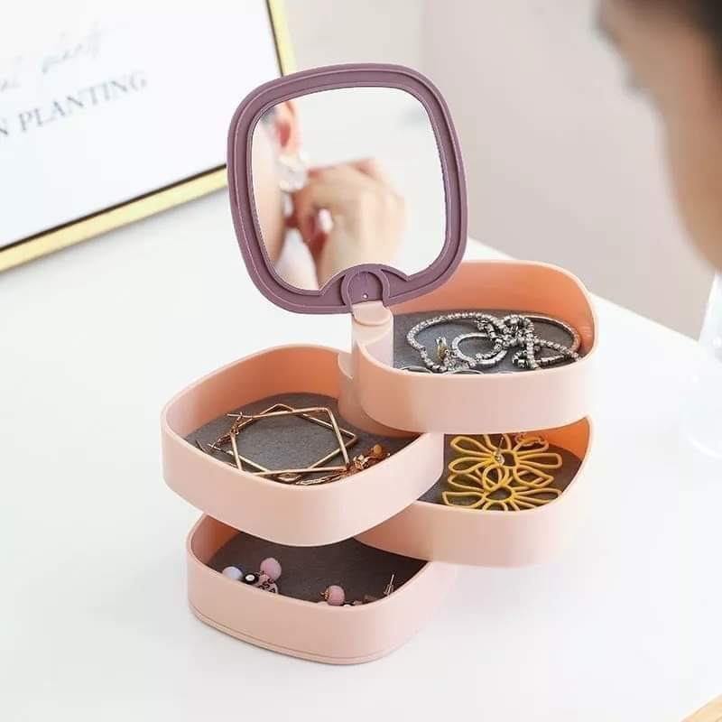 Three-tiered jewelry organizer with mirror on top, containing earrings and necklaces.