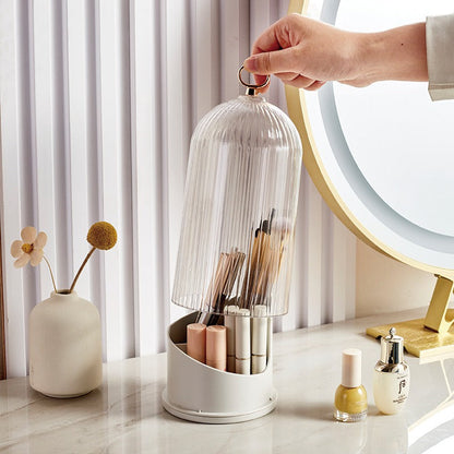 Hand holding a transparent dome over a white organizer with various items on a marble surface.