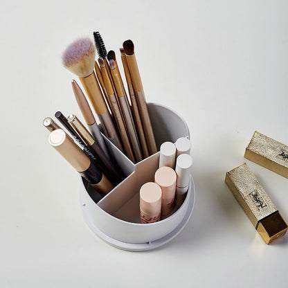 Makeup brushes and lip products in a white holder on a light gray background